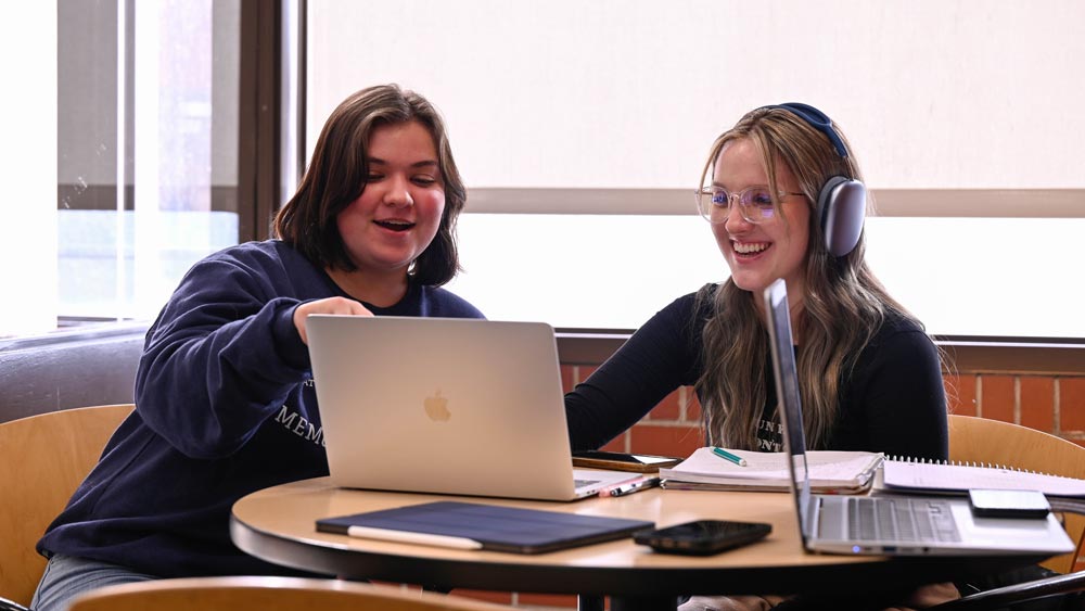 Two students looking at a laptop